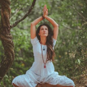 Woman meditating in a peaceful forest setting, embracing calmness and balance.