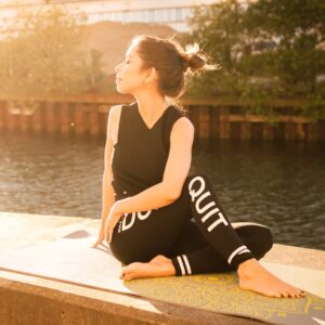 Woman practicing yoga at sunset by a serene river in Gamla Staden, Sweden.